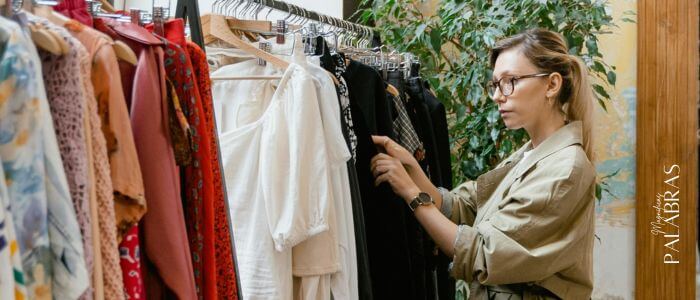 Mujer en una tienda de ropa mirando prendas en un perchero