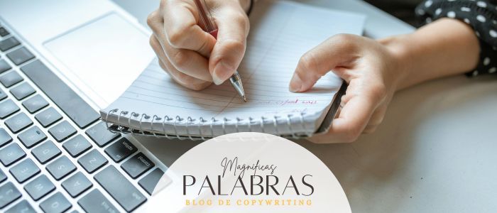 Manos escribiendo en una libreta de anillas encima de un ordenador portátil